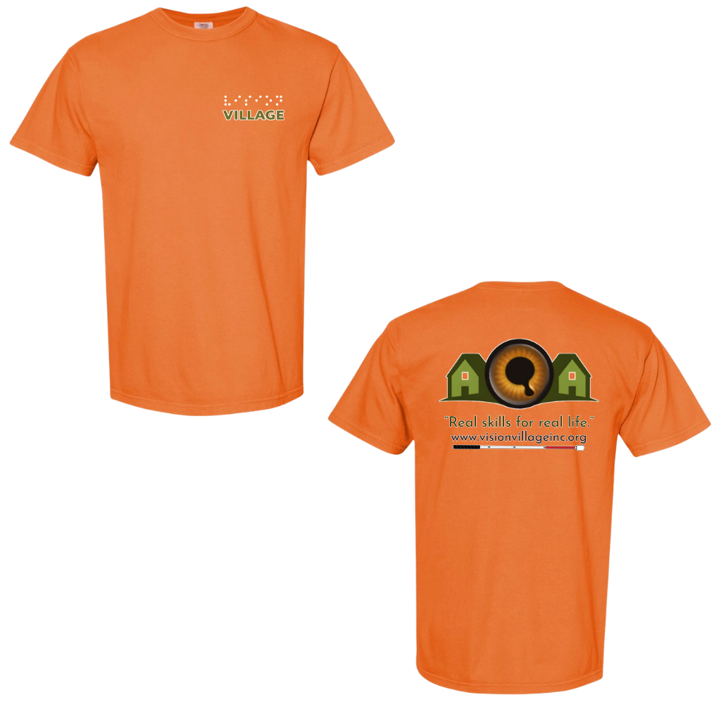 Burnt orange t-shirt with left chest graphic on the front that has the word vision in braille and the word village in print. The back has the Vision Village logo with the words “real skills for real life” underneath. Below that is the non-profit’s email address, www.visionvillageinc.org, and a graphic of a white cane.