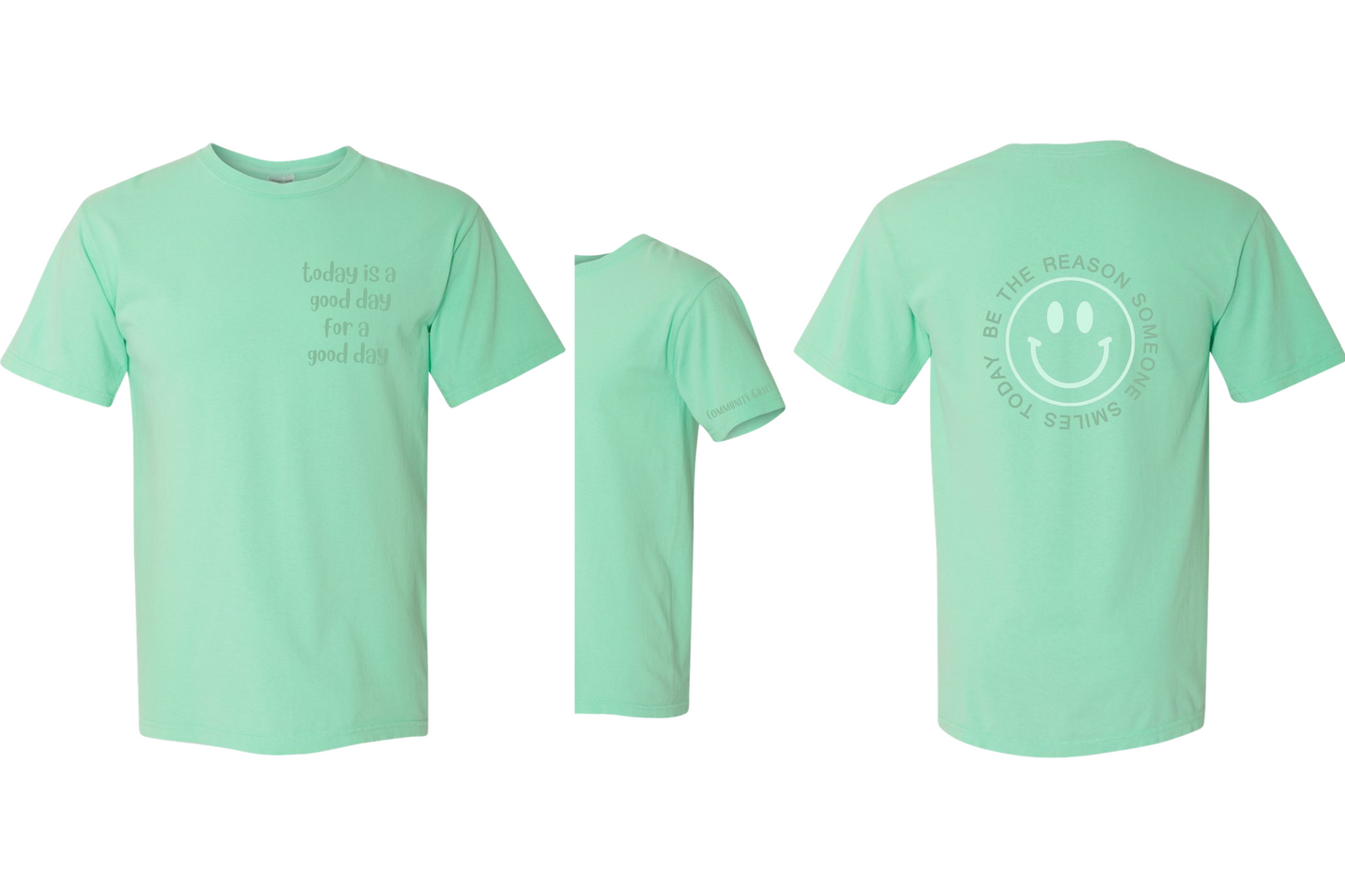 mint green short sleeve shirt with "today is a good day for a good day" on the left chest area of the shirt and Community Grace on the sleeve in dark mint green tones. On the back of the shirt there is a smiley face in a vibrant mint green color with the words "BE THE REASON SOMEONE SMILES TODAY" around it in capital letters in a darker mint green tone